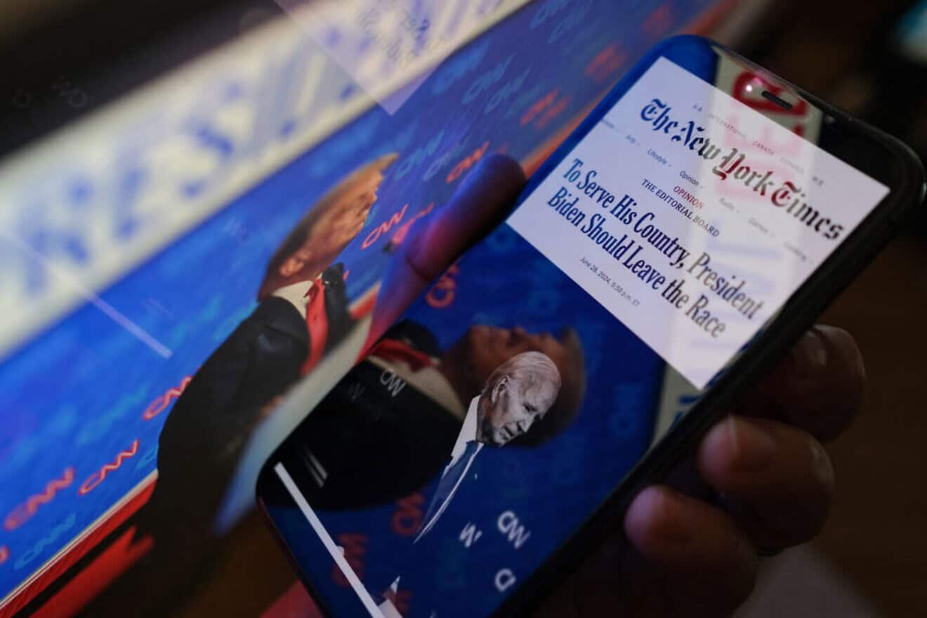 This illustrative photo shows "The New York Times" editorial calling on U.S. President Joe Biden to leave the presidential race on a smartphone screen next to a screen showing a photo of former President Donald Trump during the June 27, 2024 presidential debate, created on June 28, 2024. Photo by Chris Delmas/AFP via Getty Images.