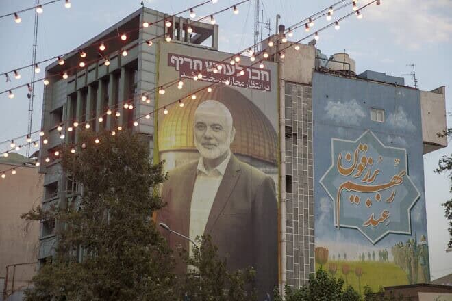Tehran University Council members attend a protest to condemn the killing of Hamas leader Ismail Haniyeh, shown in the picture at center, as they carry Iranian and PLO  flags at the university, July 31, 2024. Photo by Majid Saeedi/Getty Images.