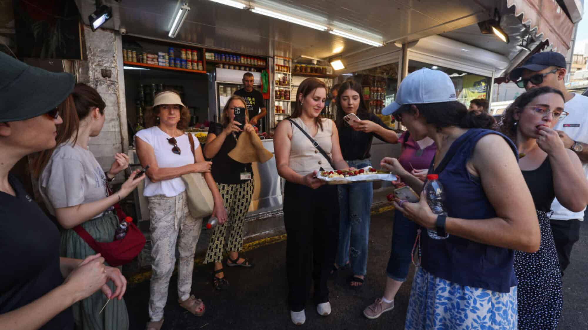 People try bites from a tasting platter offered by a shop at a market in Haifa on Aug. 5, 2024. Photo by Menahem Kahana/AFP via Getty Images.
