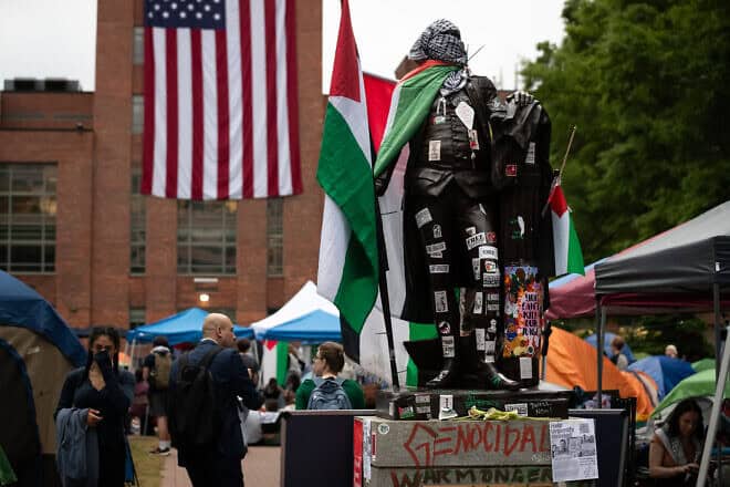 The statue of George Washington at the university that bears his name wears Palestinian flags, keffiyeh and stickers during a Gaza solidarity encampment, Washington, D.C., May 6, 2024. Photo by Allison Bailey/Middle East Images/AFP via Getty Images.