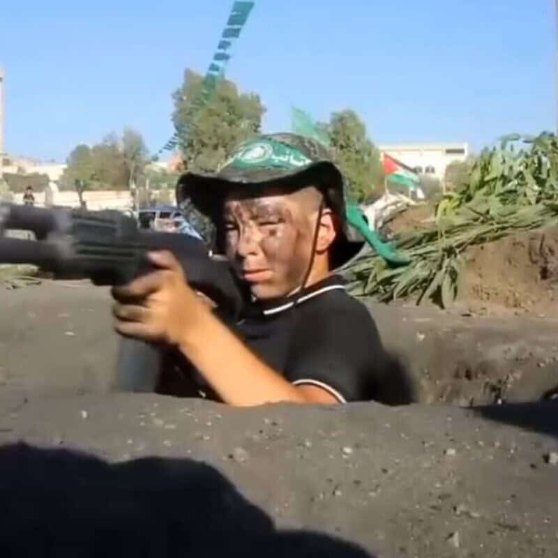 A child wields a machine gun in a clip from 'UNRWA at War'. Screenshot.