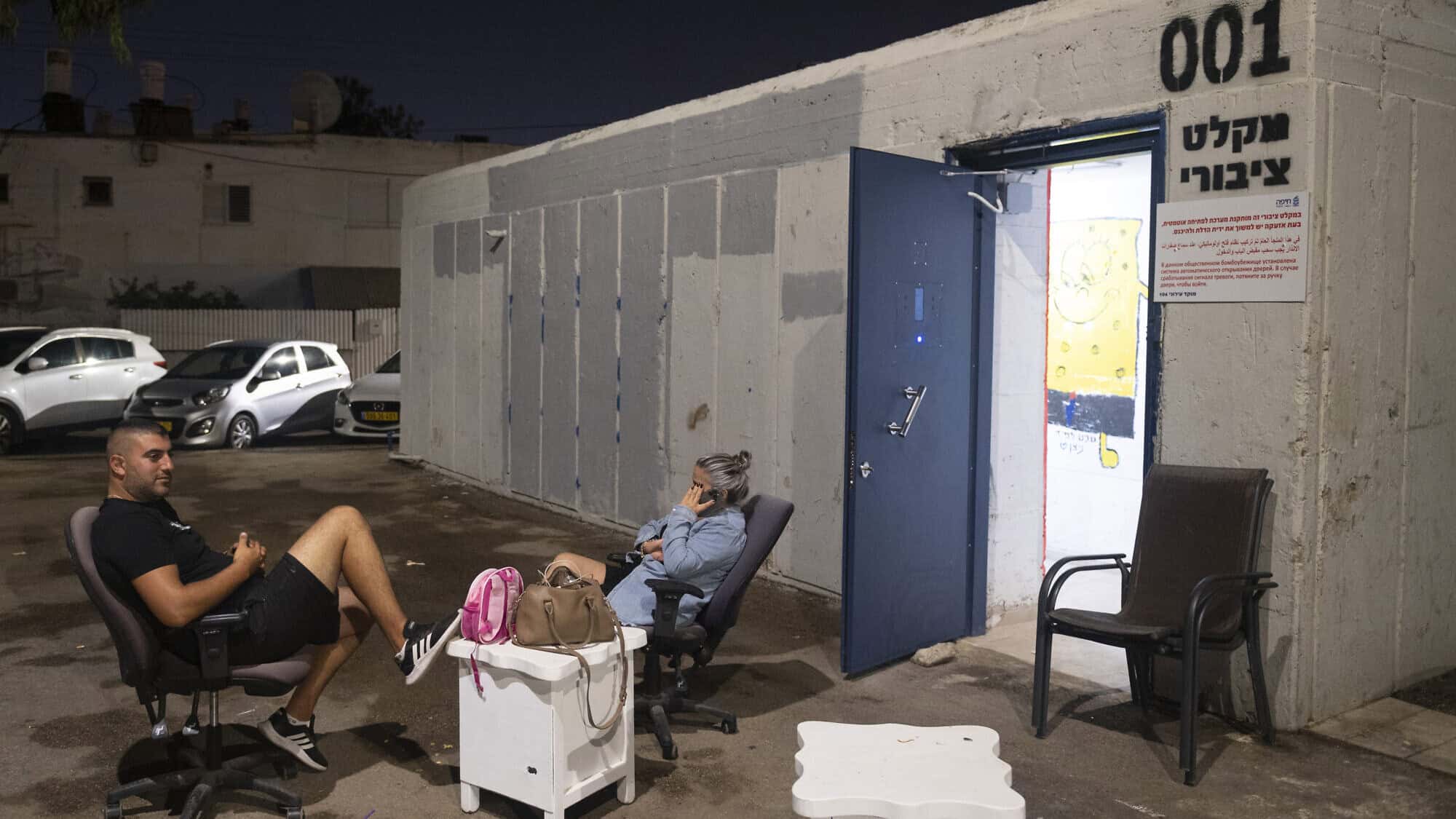 Moshe Aladi and a relative sit outside a municipal shelter in Haifa on Sept. 24, 2024. Photo by Canaan Lidor.