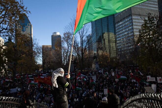A person wearing a keffiyeh waves a flag as demonstrators in support of Palestinians hold a rally to call for a ceasefire, at Dorchester Square in Montreal, Quebec, Canada, on Nov. 18, 2023. Photo by Alexis Aubin/AFP via Getty Images.