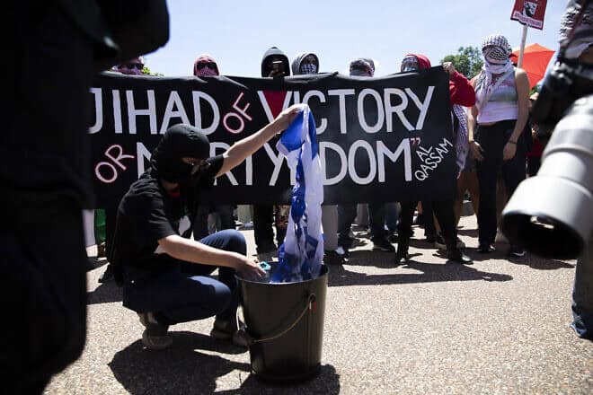 A pro-Palestinian protester is burning an Israeli flag in front of the White House during anti-Israel, anti-Western rally on June 8, 2024. Photo by Aashish Kiphayet/Middle East Images/AFP via Getty Images.