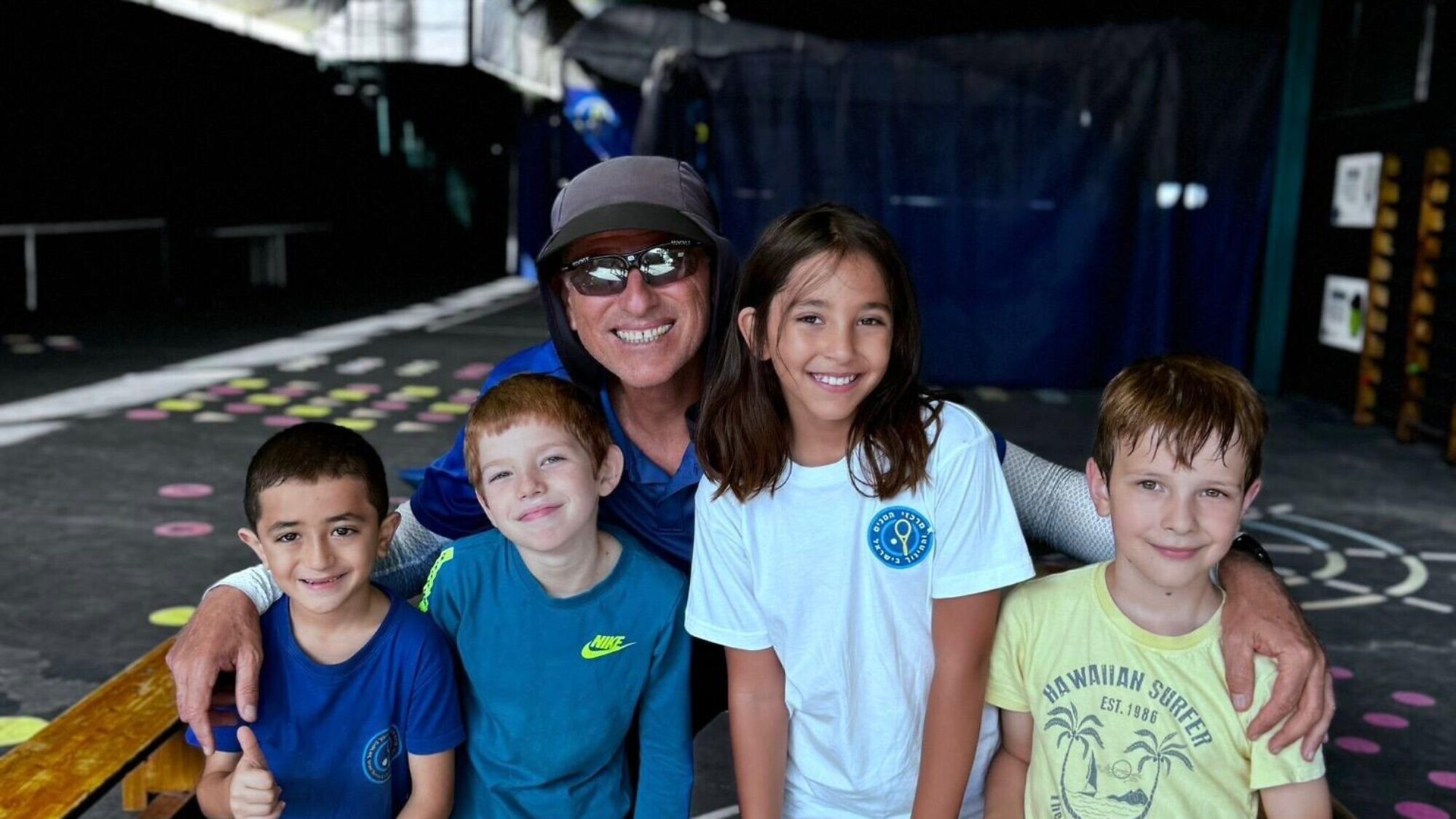 Coach Ronen Morali poses with children enrolled in the “Home Away from Home” three-day tennis camp. Photo by Alam Ibrahim.