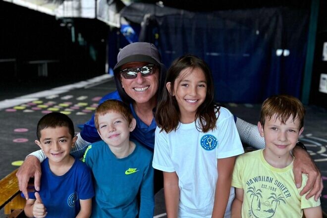 Coach Ronen Morali poses with children enrolled in the “Home Away from Home” three-day tennis camp. Photo by Alam Ibrahim.