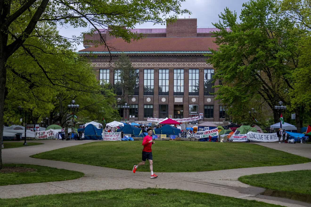 A runner passes the pro-Palestinian, pro-Hamas and anti-Israel Gaza solidarity encampment on University of Michigan's campus in Ann Arbor on May 4, 2024, Photo by Nic Antaya/Getty Images.