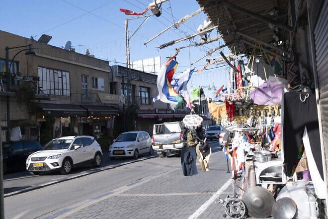 Israeli and Druze flags fly on a store front on the deserted main shopping street of Daliyat al-Karmel, near Haifa, on Oct. 21, 2024. Photo by Canaan Lidor.