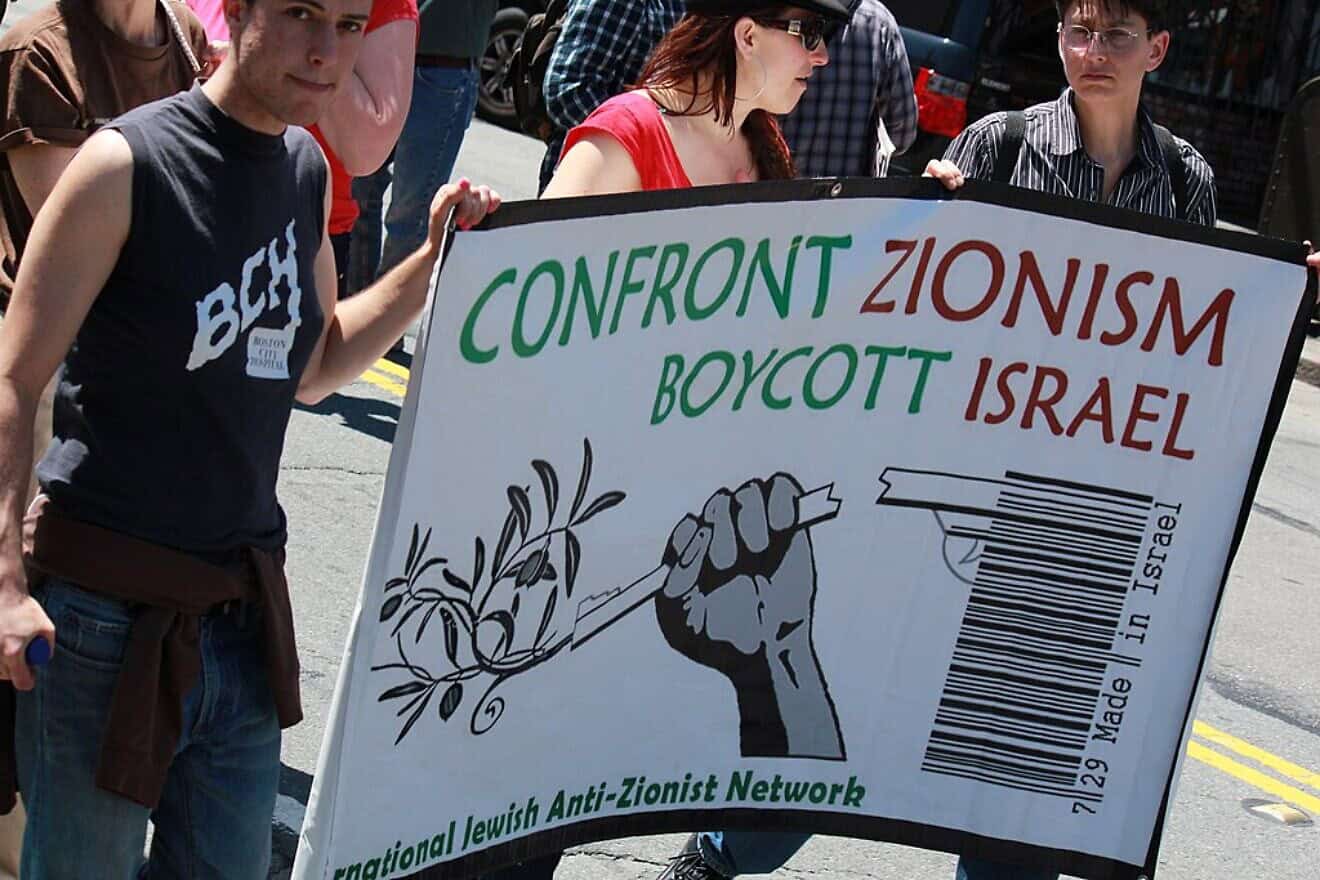 Individuals holding a Confront Zionism, Boycott Israel sign during a demonstration. Credit: Wikimedia Commons.