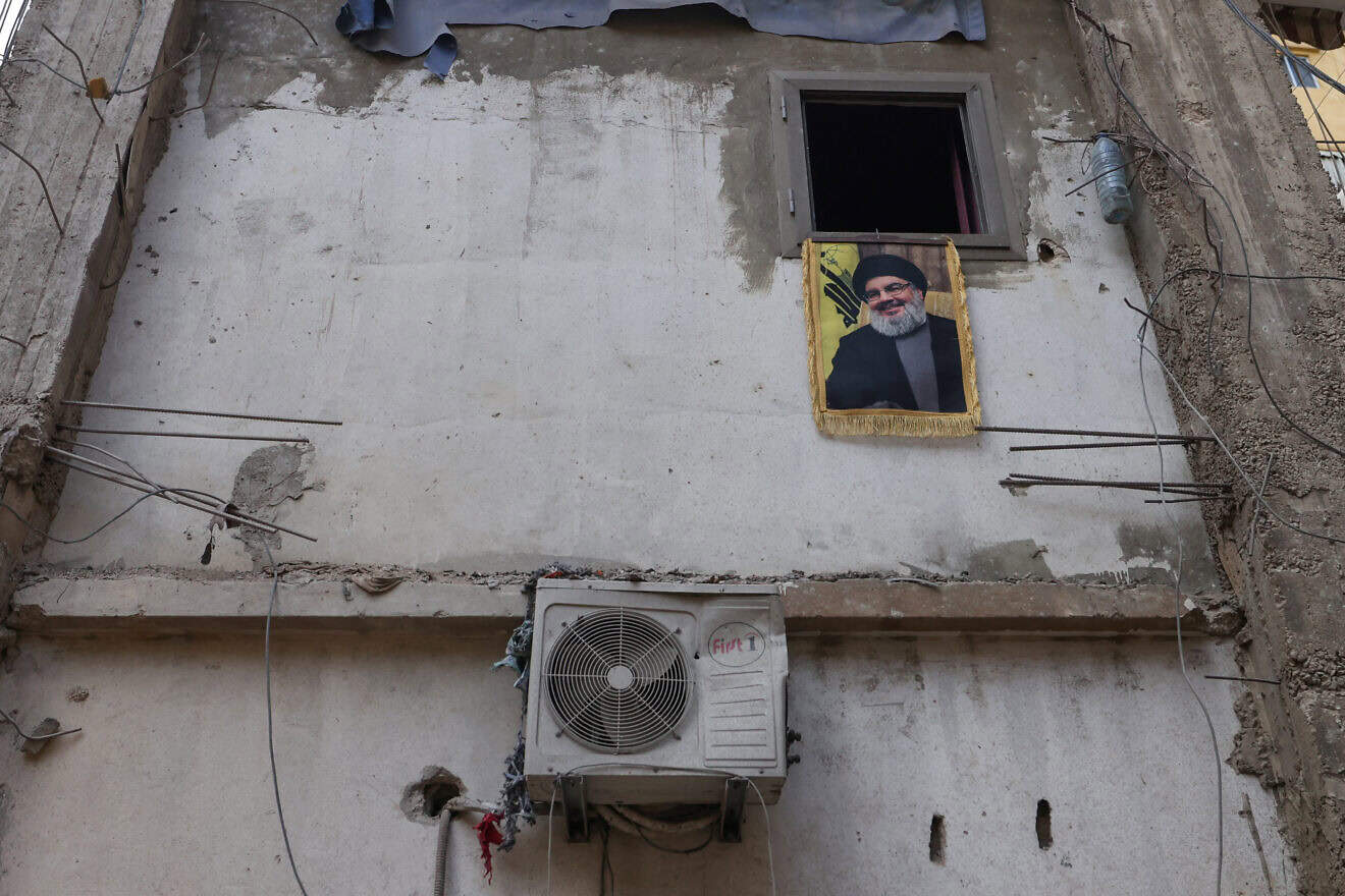 A portrait of slain Hezbollah chief Hassan Nasrallah hangs from a window at the site of an Israeli airstrike in al-Shiyah neighborhood in Beirut's southern suburbs on Nov. 19, 2024. Photo by Anwar Amro/AFP via Getty Images.