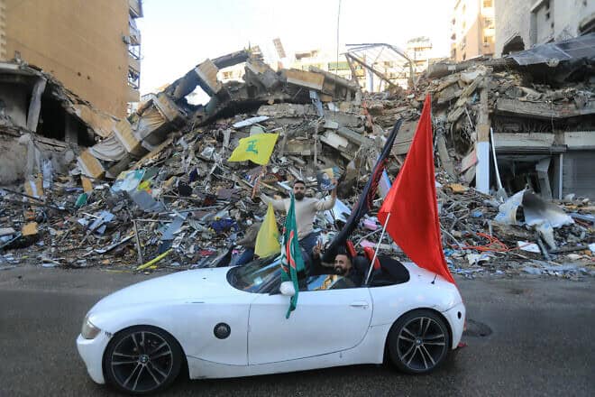 A driver waves the flag of Hezbollah as supporters of the terrorist group parade in Beirut's southern suburbs after a ceasefire between Israel and the Lebanese terrorist group took effect, Nov. 27, 2024. Photo by AFP via Getty Images.