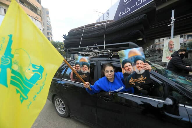 A Lebanese woman holds up portraits of Hezbollah's slain leaders Hassan Nasrallah and Hashem Safieddine as supporters of the terrorist group parade in Beirut's southern suburbs after a ceasefire is put in place between Israel and Lebanon, Nov. 27, 2024. Photo by AFP via Getty Images.