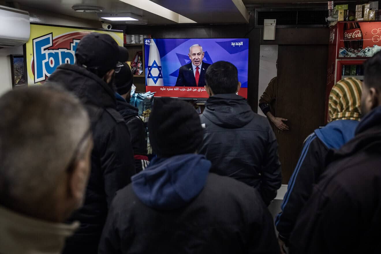 People in Lebanon watch Israeli Prime Minister Benjamin Netanyahu announce his Cabinet's approval of a ceasefire, near Martyrs Square in Beirut, Nov. 26, 2024. Photo by Ed Ram/Getty Images.