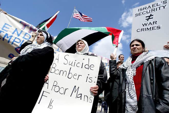From left: Maha Ali of Arlington, Va., Janine Ali of Washington, D.C., and Hidaya Wandan of Falls Church, Va., hold pro-Palestinian signs and flags during a rally outside the U.S. State Department, where about a dozen protesters were arrested on April 5, 2002. Photo by Tim Sloan/AFP via Getty Images.