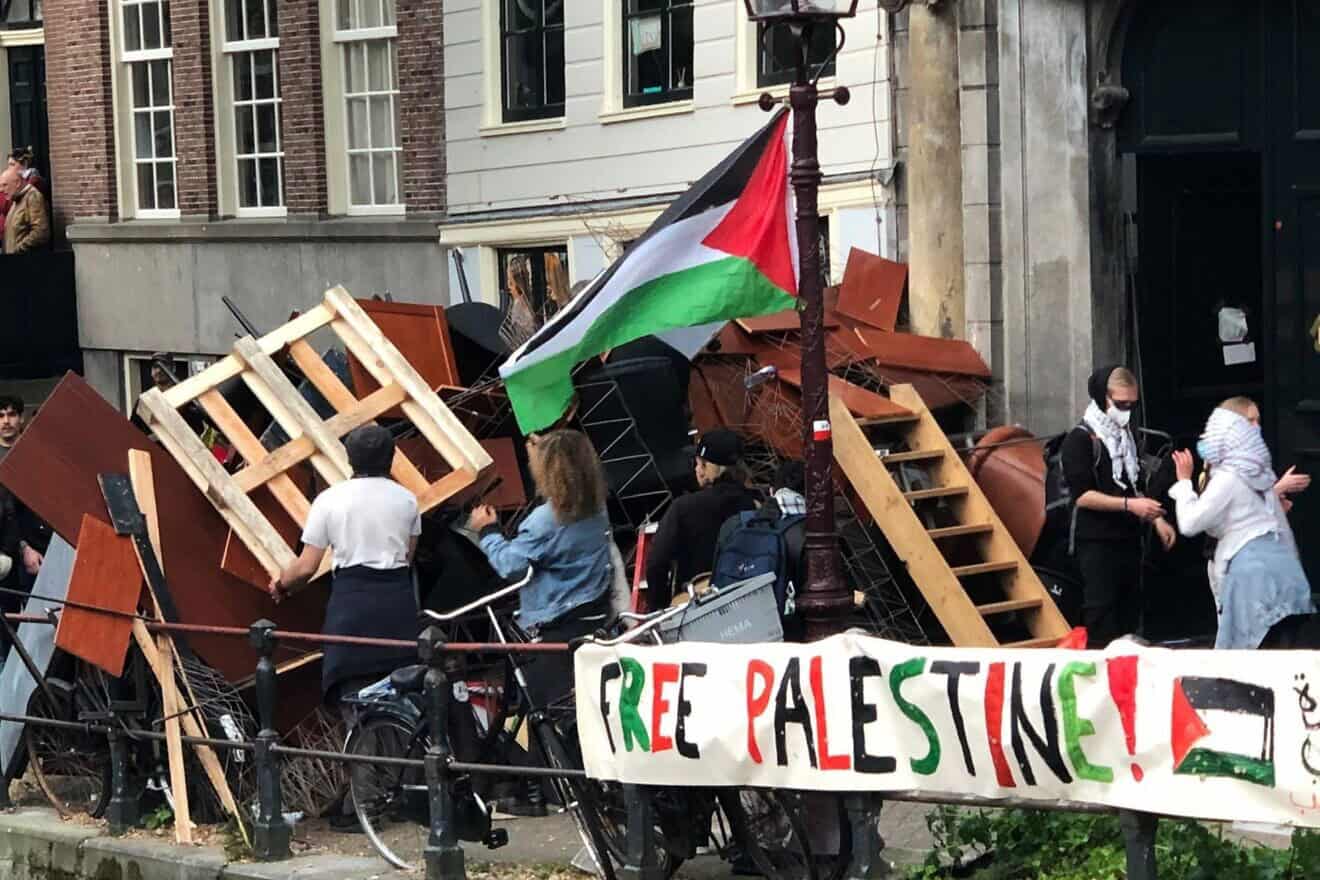 Demonstrators reinforce a barricade at an anti-Israel tent encampment at the University of Amsterdam, six months to the day after a violent citywide attack against Maccabi Tel Aviv soccer fans, on May 7, 2024. Credit: Umbrellafighter via Wikimedia Commons.