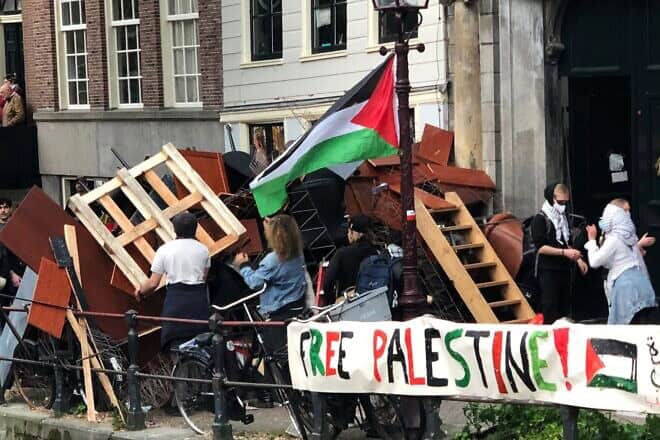 Demonstrators reinforce a barricade at an anti-Israel tent encampment at the University of Amsterdam, six months to the day after a violent citywide attack against Maccabi Tel Aviv soccer fans, on May 7, 2024. Credit: Umbrellafighter via Wikimedia Commons.