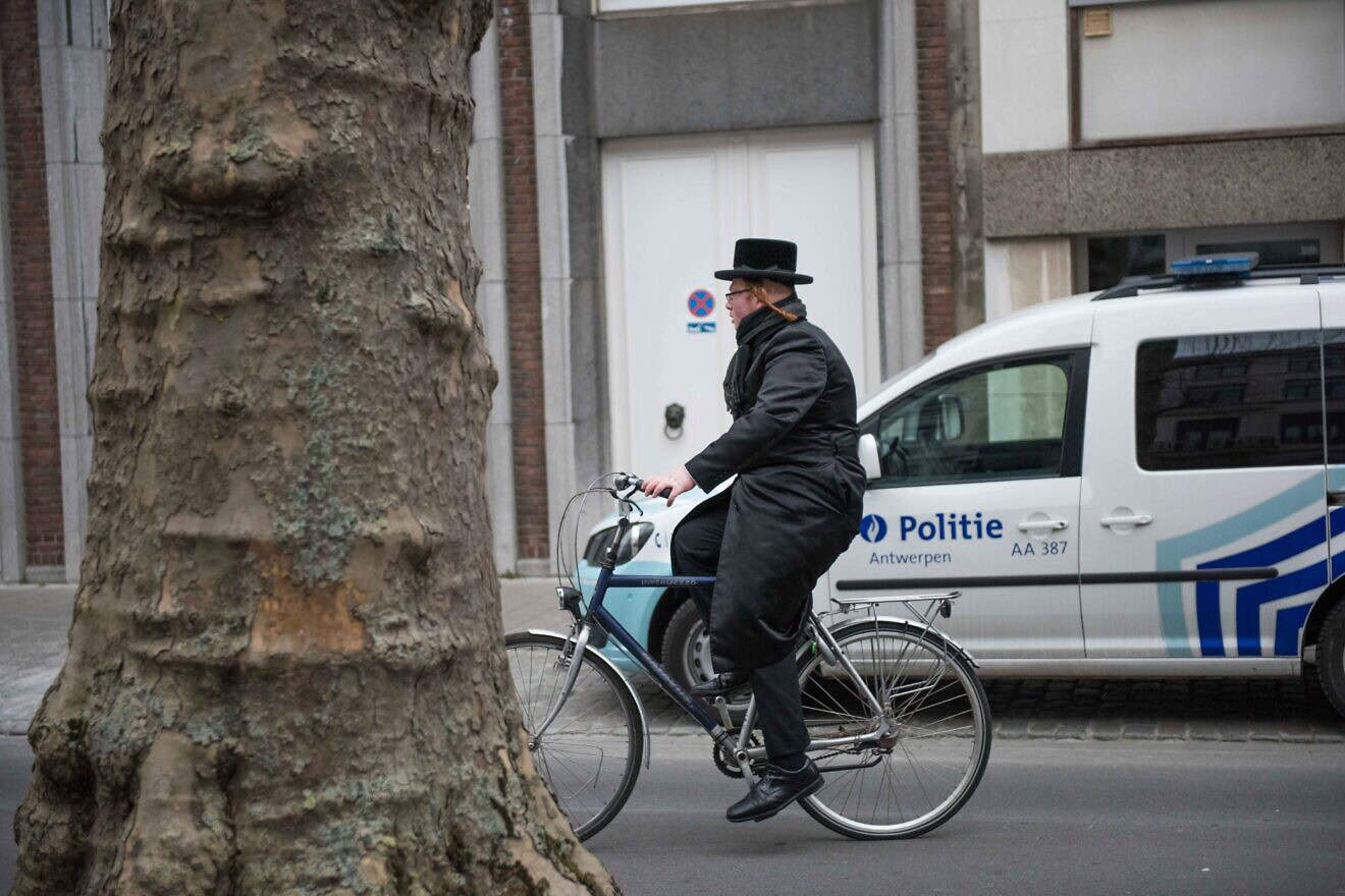 A Jewish man cycles past a police car in Antwerp, Belgium, on March 24, 2016. Photo by Canaan Lidor.