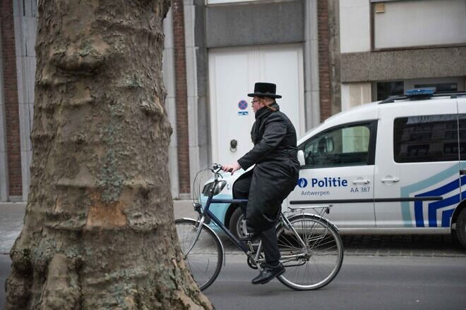 A Jewish man cycles past a police car in Antwerp, Belgium, on March 24, 2016. Photo by Canaan Lidor.
