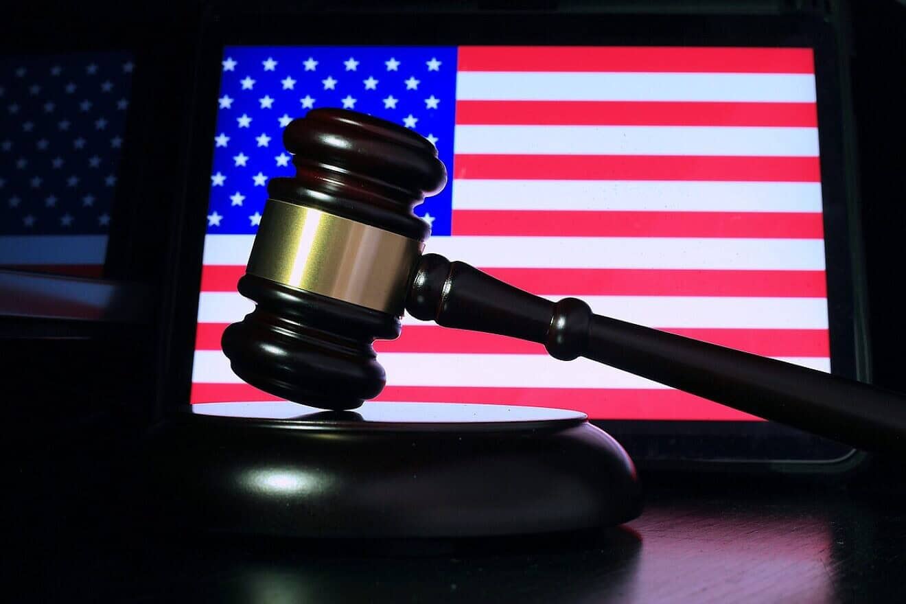 A gavel in front of a screen displaying the U.S. flag. Credit: Sergei Tokmakov/Pixabay