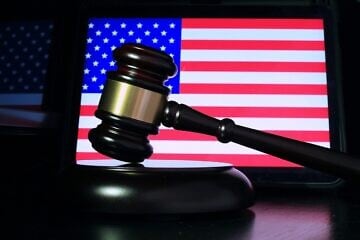 A gavel in front of a screen displaying the U.S. flag. Credit: Sergei Tokmakov/Pixabay