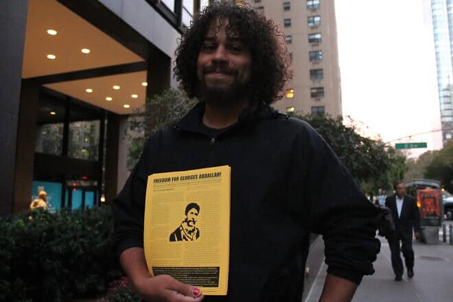 A demonstrator holds a flier bearing the portrait of George Ibrahim Abdallah outside the mission of France to the United Nations in New York on Oct. 16, 2017. Photo by Joe Catron/Flickr.