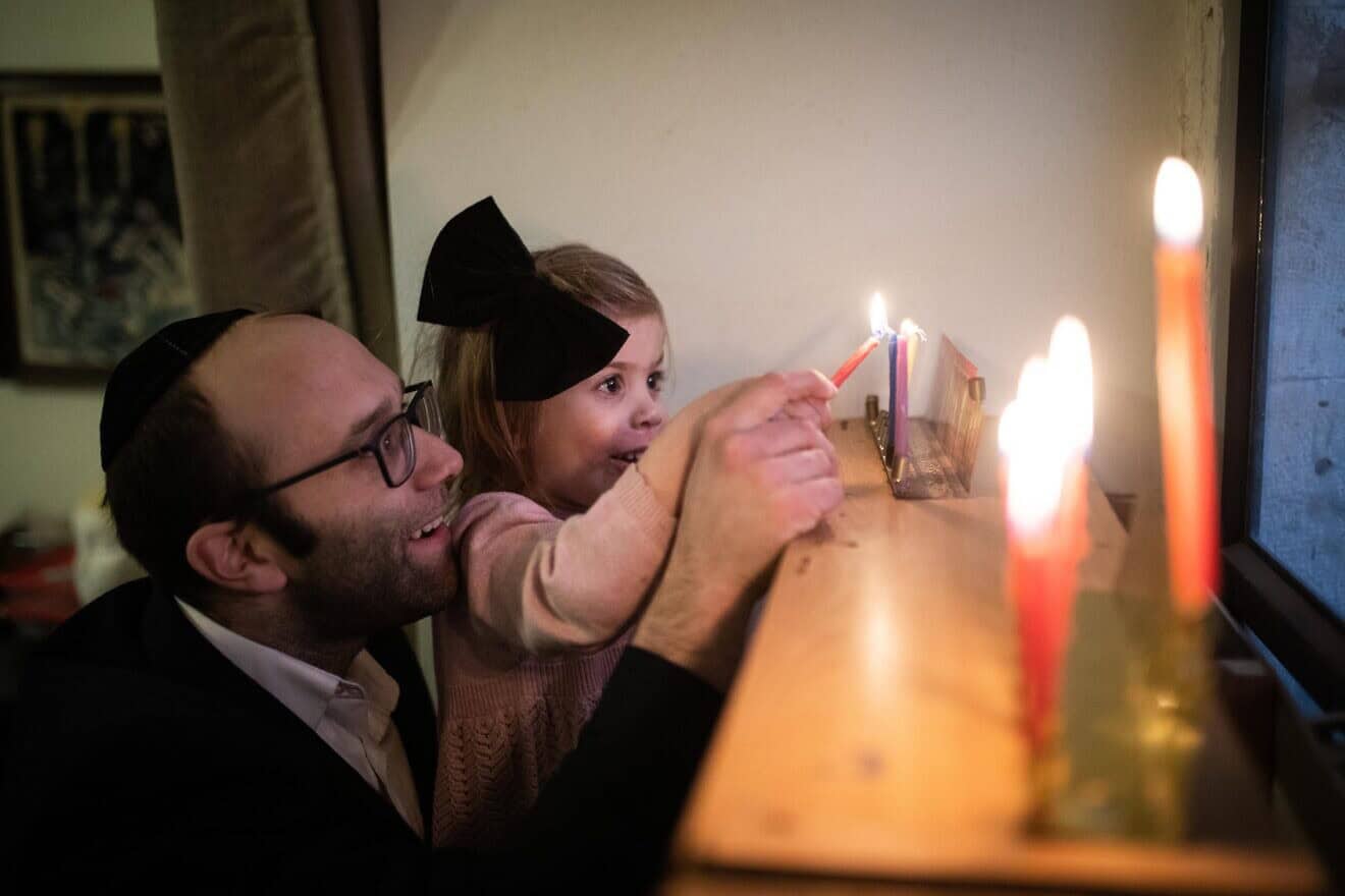 A family lights the chanukiyah in Jerusalem's Nachlaot neighborhood, on the third night of Chanukah, on Dec. 24, 2019. Photo by Hadas Parush/Flash90.