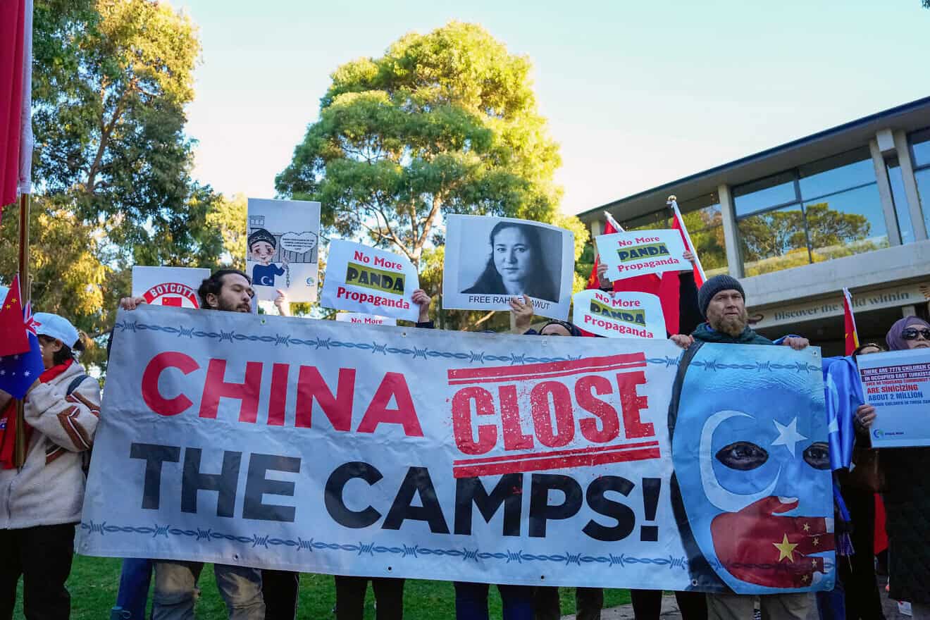 Uyghur and counter-China demonstrators hold a banner and placards as they await the arrival of China's Premier Li Qiang at the Adelaide Zoo in south Australia on June 16, 2024. Photo by Asanka Ratnayake/POOL/AFP via Getty Images.
