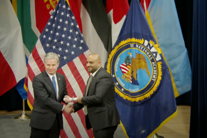 Christopher Wray, the director of the FBI, hands a diploma to a graduate identified as Husham Abu-Aisha at FBI National Academy in Quantico graduation, Dec. 12, 2024. Source: YouTube/National Academy.