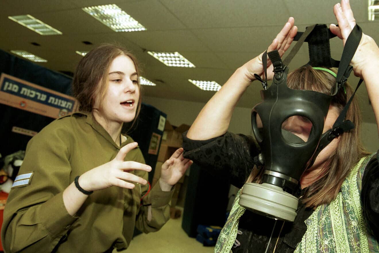A soldier teaches a woman how to wear and use a gasmask during the Second Intifada, Oct. 30, 2001. Credit: Flash90.
