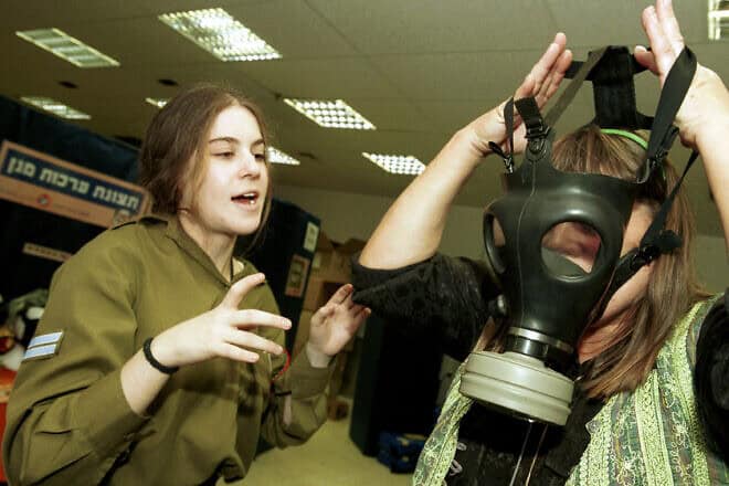 A soldier teaches a woman how to wear and use a gasmask during the Second Intifada, Oct. 30, 2001. Credit: Flash90.