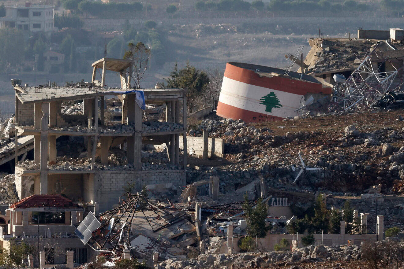 An Israeli flag on a destroyed building, and a Lebanese flag painted on a damaged building in the southern Lebanese village of Meiss el-Jabal, Nov. 25, 2024. Photo by Jalaa Marey/AFP via Getty Images.
