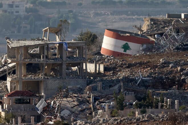 An Israeli flag on a destroyed building, and a Lebanese flag painted on a damaged building in the southern Lebanese village of Meiss el-Jabal, Nov. 25, 2024. Photo by Jalaa Marey/AFP via Getty Images.