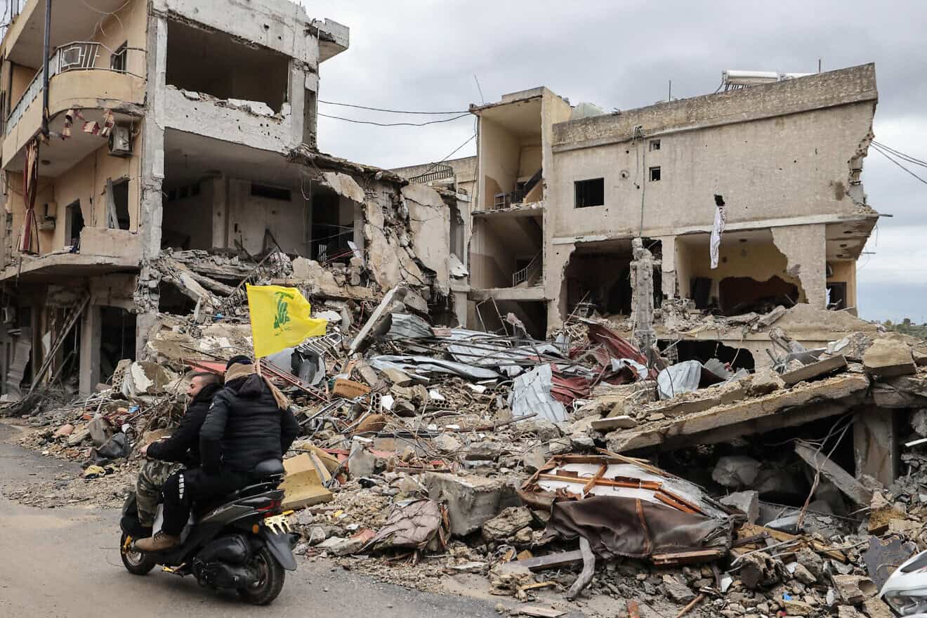 Men ride a scooter with a Hezbollah flag past destroyed buildings in the south of Lebanon after a ceasefire is put into place between Israel and Hezbollah, Nov. 27, 2024. Photo by Anwar Amro/AFP via Getty Images.