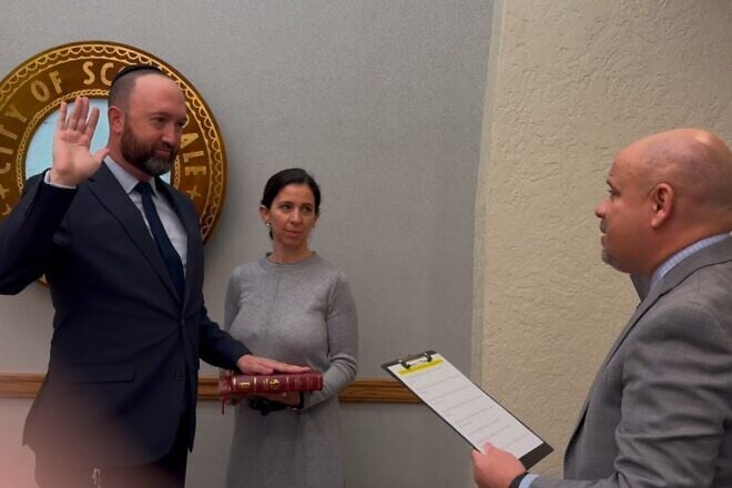 Adam Kwasman is sworn in as a member of the Scottsdale City Council in Arizona on his family's copy of a Hebrew Bible published by the late renowned Rabbi Adin Steinsaltz, as his wife Orit Kwasman looks on, Dec. 9, 2024. Credit: Courtesy of Adam Kwasman.