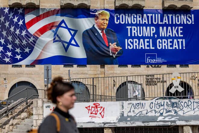 Pepole walk in central Jerusalem next to a sign congratulating Donald Trump for his victory in the U.S. presidential election, Nov. 7, 2024. Photo by Yonatan Sindel/Flash90.