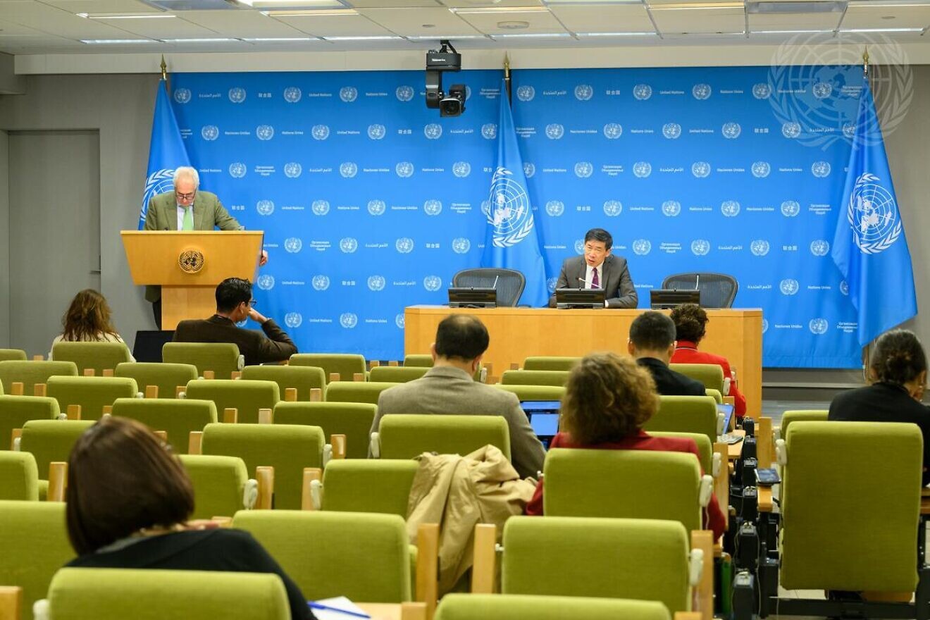 Stéphane Dujarric, spokesman for the U.N. secretary-general, stands at the podium at a United Nations press briefing, as Xu Haoliang, associate administrator of the U.N. Development Programme, sits at the dais, New York City, on Dec. 11, 2024. Credit: Loey Felipe/U.N. Photo.