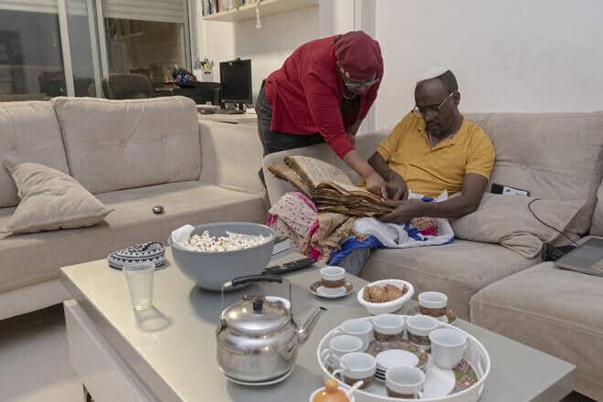 Ayanawo Ferada Senebato and his wife, Mare, read a copy of the Orit, Ethiopian Jewry's version of the Hebrew Bible, at their home in Rishon Letzion, Israel, on Oct. 30, 2024. Photo by Canaan Lidor.