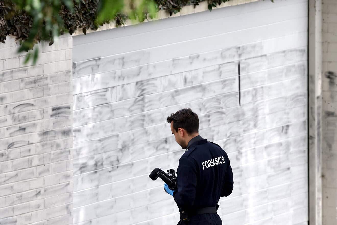 A forensics police officer takes photographs of the wall where anti-Israel graffiti has been removed in the Sydney suburb of Woollahra on Dec. 11, 2024. Photo by David Gray/AFP via Getty Images.