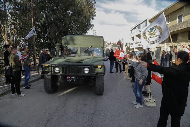 People lift national flags in the Maronite Catholic village of Qlayaa as they offer sweets to passing cars including a Lebanese army vehicle, to celebrate the election of a president for Lebanon on Jan. 9, 2025. Photo by AFP via Getty Images.