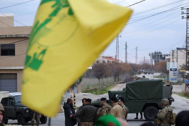 A resident of Southern Lebanon flies a Hezbollah flag near Lebanese Armed Forces soldiers on Jan. 26, 2025. Photo by Rabih Daher/AFP via Getty Images.