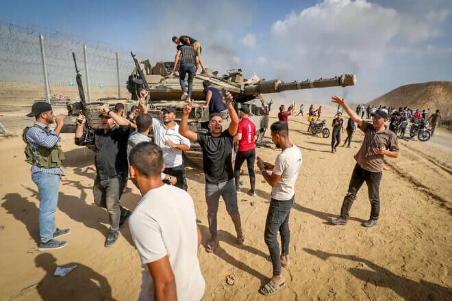 Palestinians take control of an IDF tank after breaching the Israeli border fence from Khan Yunis in the southern Gaza Strip, Oct. 7, 2023. Photo by Abed Rahim Khatib/Flash90.