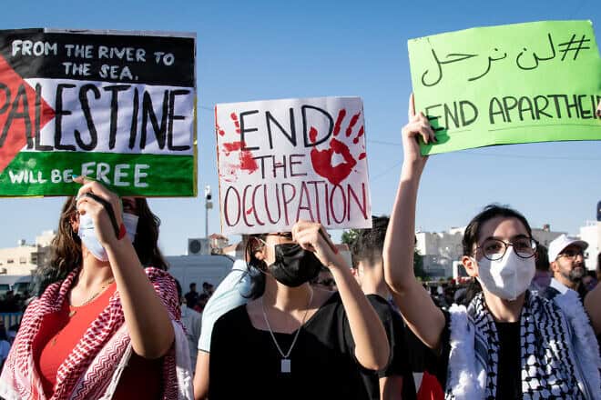 Pro-Palestinian demonstrators hold signs anti-Zionist signs during Israel's 11-day conflict against Hamas in Gaza, the IDF's “Operation Guardian of the Walls,” in May 2021. Credit: Raya Sharbain via Wikimedia Commons.