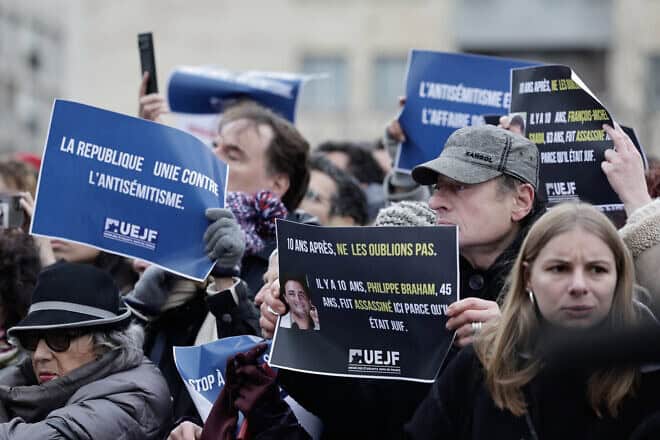 Attendees of a rally in France sponsored by the Representative Council of French Jewish Institutions (CRIF) hold signs reading, “The republic united against antisemitism” and “10 years on, let's not forget” outside the Hypercacher kosher market in Paris, in memory of the terrorist attack that took place there a decade ago, on Jan. 9, 2025. Photo by Stephane De Sakutin/AFP via Getty Images.