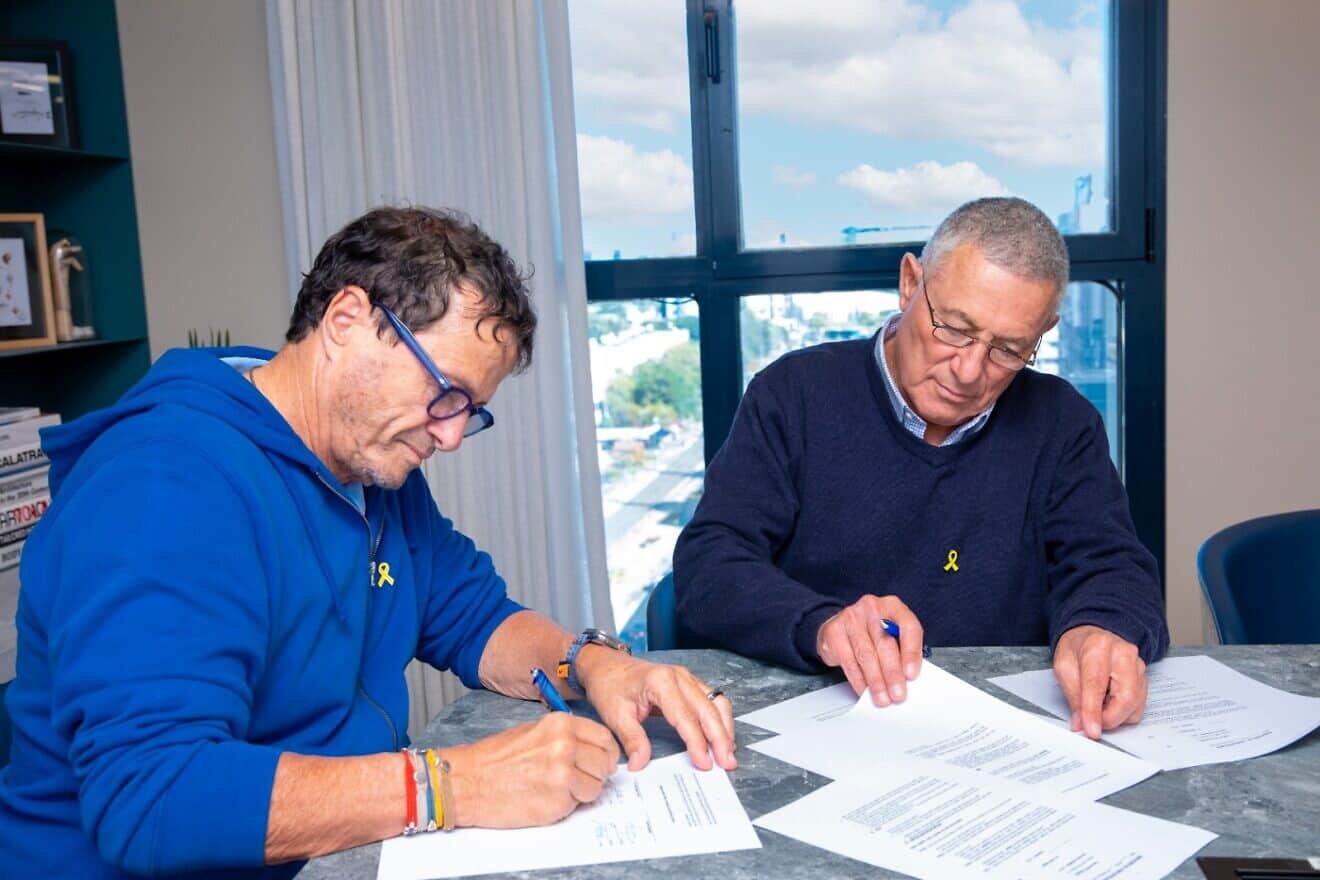 Businessman Udi Angel (left) and Doron Almog, chairman of the Jewish Agency for Israel, sign an agreement to create a relief fund for businesses in northern Israel. Photo by Inbal Marmary.