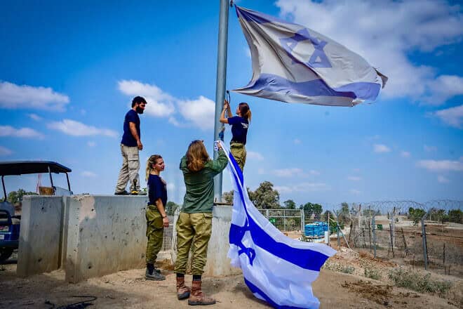 Israeli soldier hang an Israeli flag in Kibbutz Nir Am, near the Israeli border with the Gaza Strip, on Aug. 12, 2024. Photo by Avshalom Sassoni/Flash90.