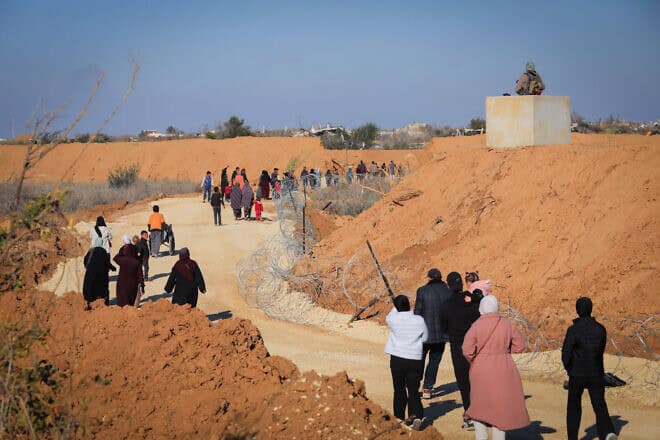 Gazans walk alongside an Israeli army post in northern Gaza, Jan. 28, 2025. Photo by Ali Hassan/Flash90.
