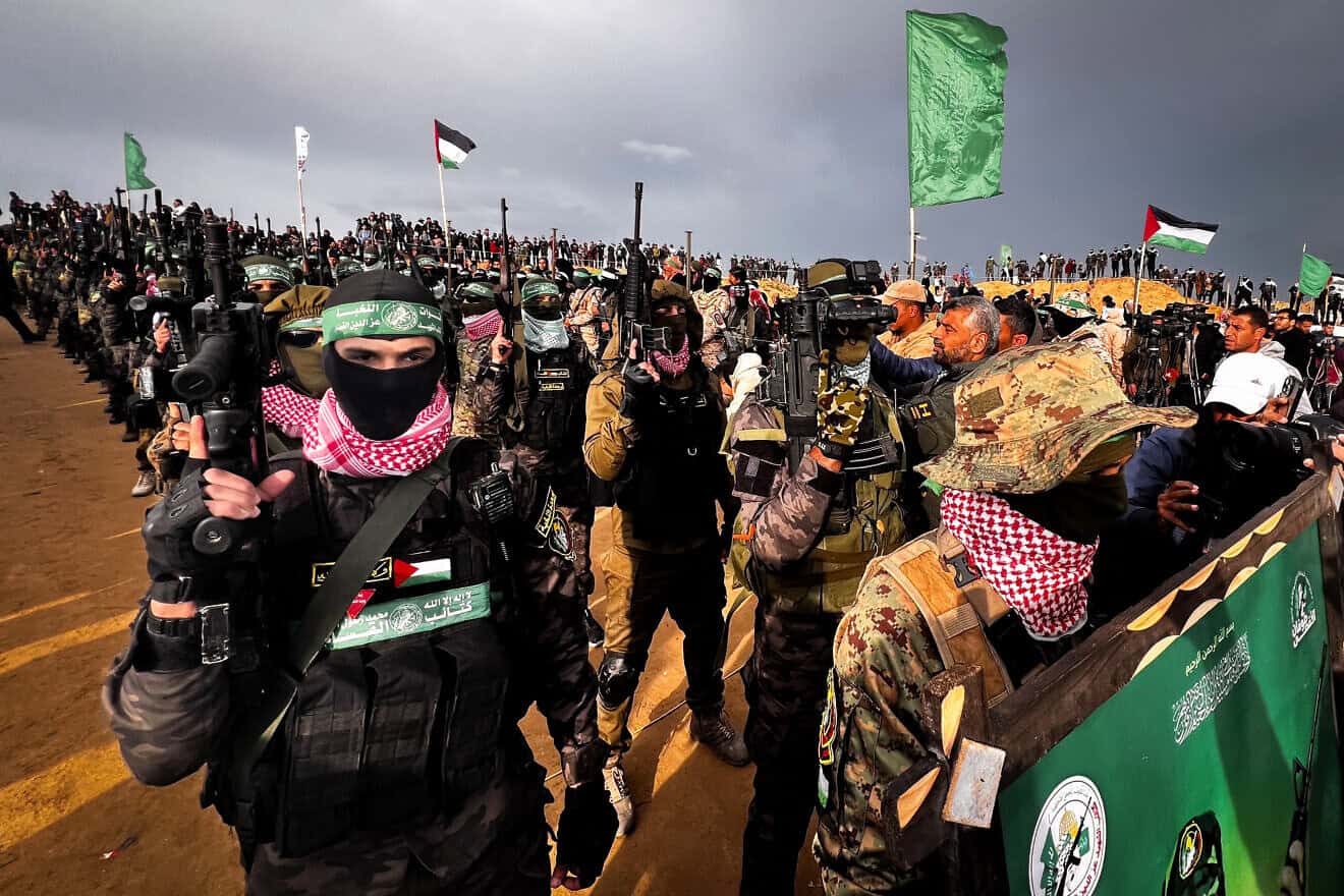 Al-Qassam Brigades terrorists stand guard while Palestinians wait for the handover of the bodies of four Israeli hostages to the Red Cross in Khan Yunis, the Gaza Strip, Feb. 20, 2025. Photo by Saeed Mohammed/Flash90.
