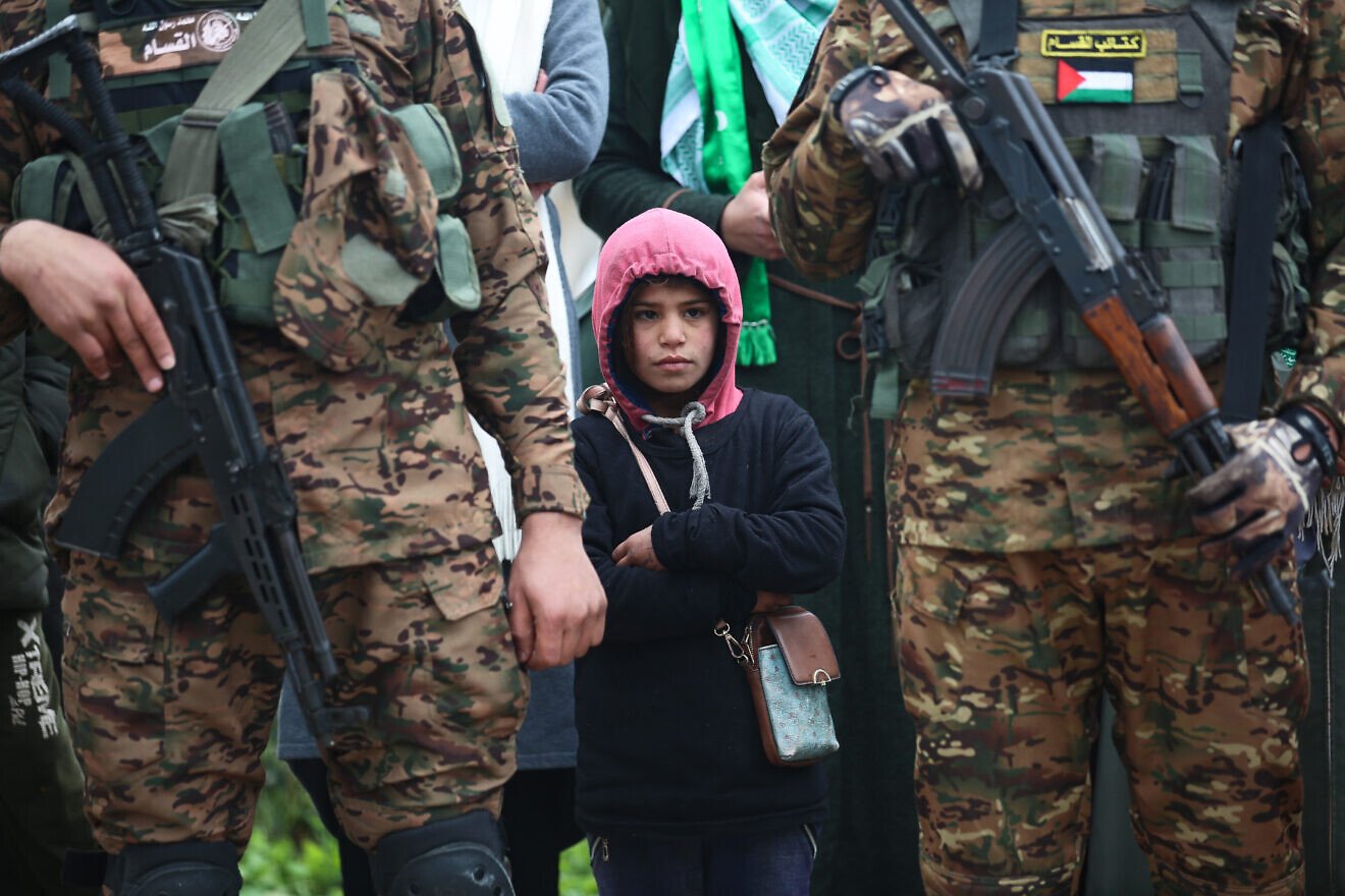 Hamas terrorists watch a propaganda ceremony during which Israeli hostages are turned over to the Red Cross, Gaza Strip, Feb. 22, 2025. Credit: Ali Hassan/Flash90.