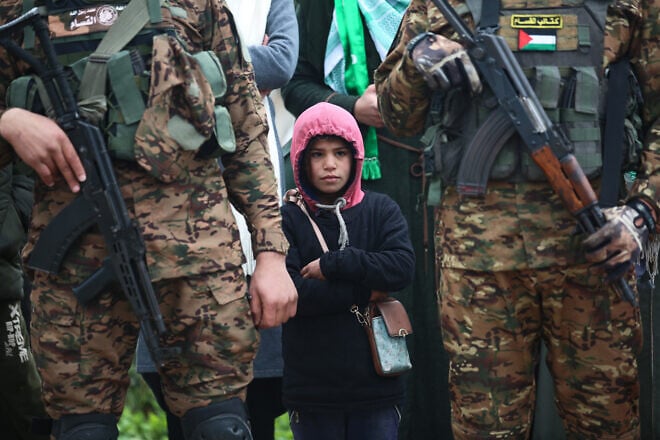Hamas terrorists watch a propaganda ceremony during which Israeli hostages are turned over to the Red Cross, Gaza Strip, Feb. 22, 2025. Credit: Ali Hassan/Flash90.