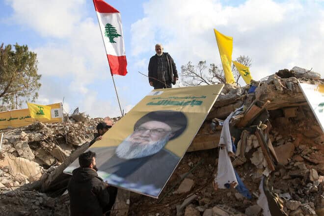 People place a picture of slain Hezbollah leader Hassan Nasrallah over the rubble of the shrine of Shamoun al-Safa, built within a castle in the village of Shamaa in Southern Lebanon's Tyre governorate, Jan. 31, 2025. Photo by Mahmoud Zayyat/AFP via Getty Images.